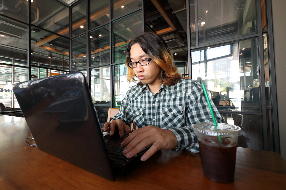 Junior Programmer working on a laptop with an iced coffee