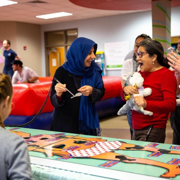 Women laughing while playing a life-size version of the Operation board game