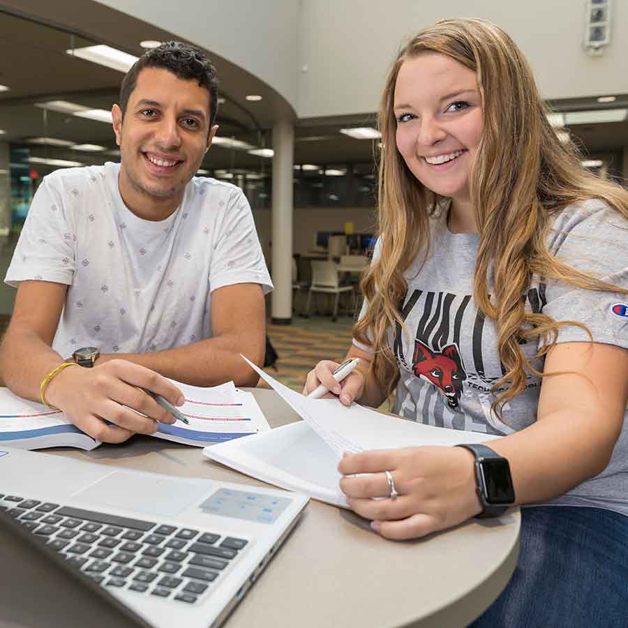 Two students studying together and smiling