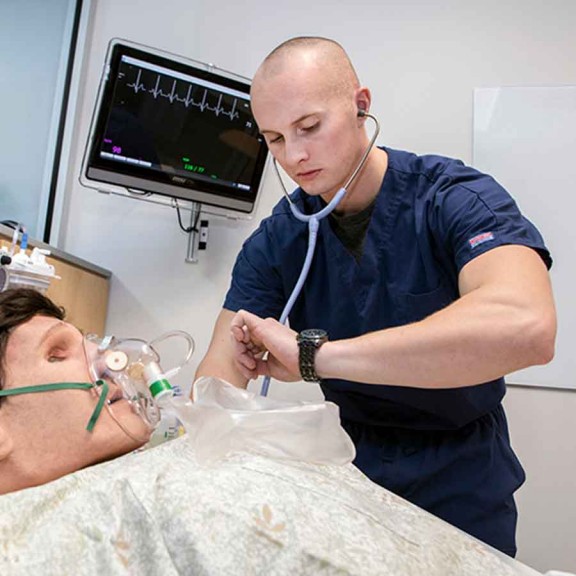 Student with stethoscope and mannequin patient