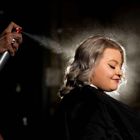Stylist spraying hairspray onto client's hair